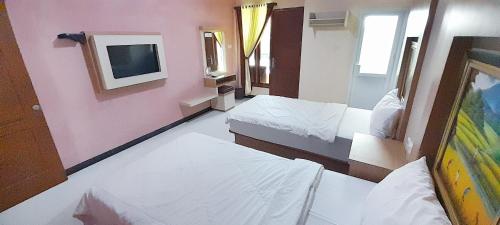 a room with two beds and a tv on the wall at Montana Hotel Kuningan in Panawuan