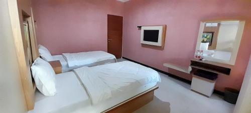 a pink room with two beds and a sink at Montana Hotel Kuningan in Panawuan