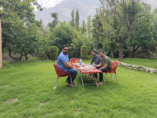 tre uomini seduti a un tavolo sull'erba di Qasr اشرف a Skardu