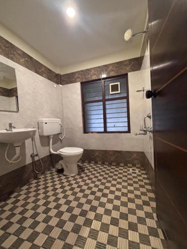 a bathroom with a toilet and a sink and a window at Jaya Tourist Home in Varkala