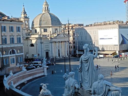 Una statua nel mezzo di una città con edifici di Roman Babuino Inn a Roma