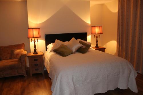 a bedroom with a bed with two lamps and a chair at The Twelve Oaks in Kenmare