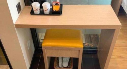 a table with a yellow stool under a table at IU Hotel Taiyuan Changfeng West Street The Mixc in Taiyuan