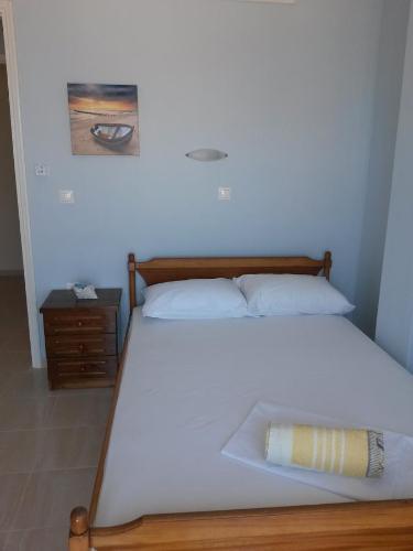 a white bed with a wooden frame and a night stand at Drakopanagiotaki Rooms in Agios Andreas