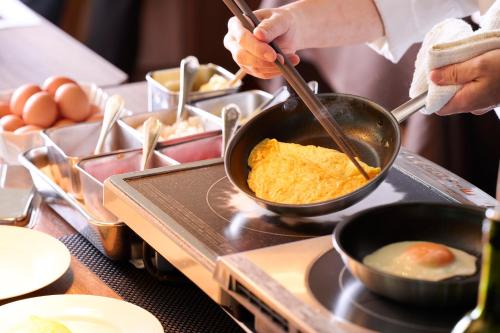 a person cooking food in a pan on a stove at Marunouchi Hotel in Tokyo