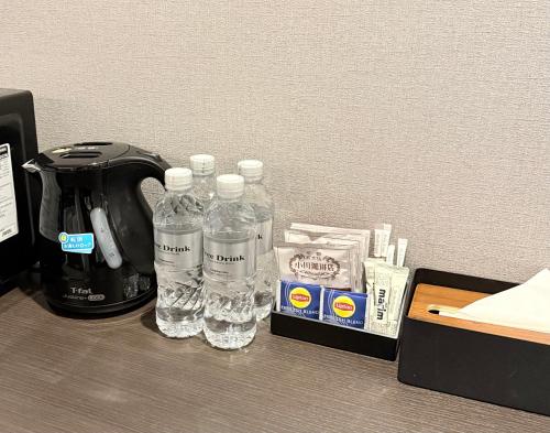 two bottles of water sitting next to a coffee maker at Kyohotel Kishotei Goshominami in Kyoto