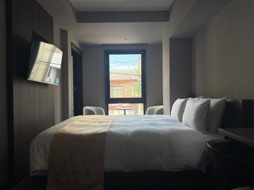 una camera da letto con un grande letto bianco con una finestra di hotel bolam kyoto a Shimo-dachiyuuridōri