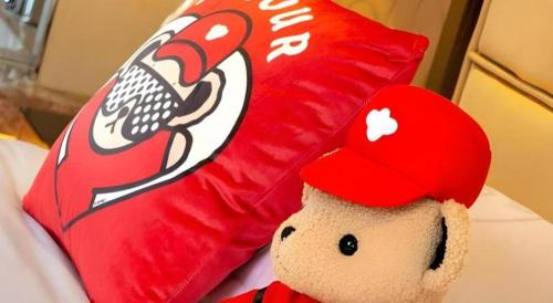 a stuffed teddy bear wearing a red hat next to a pillow at Radegast Hotel CBD in Beijing
