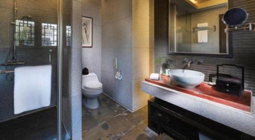 a bathroom with a sink and a toilet and a mirror at Hotel Dayu Kaiyuan in Shaoxing