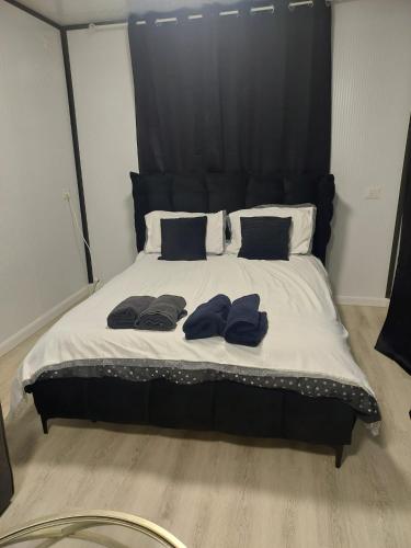 a bed with a black headboard and two robes on it at בקתה על הנחל in Yuval