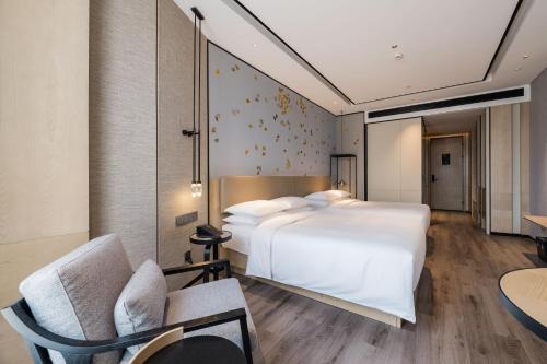 a bedroom with a large white bed and a chair at Shanghai Yunhe Yebo Hotel, Wuning Road Global Harbor Branch in Shanghai