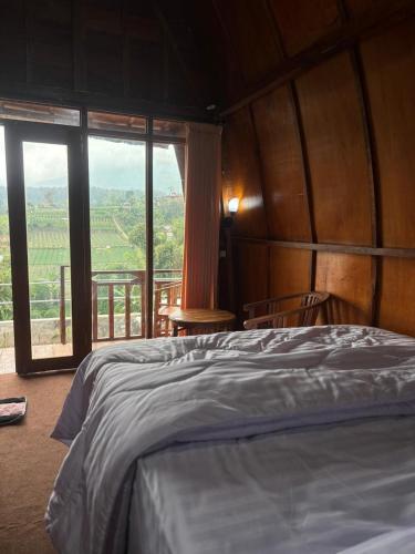 a bedroom with a bed and a large window at Pondok Kebun Sayur in Bedugul