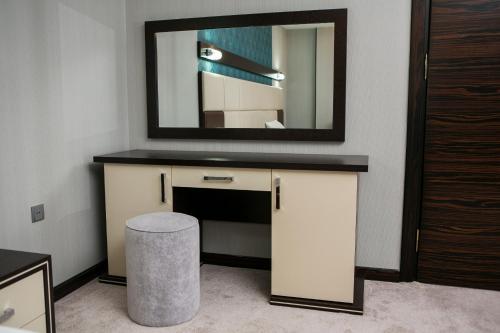 a bathroom with a vanity with a mirror and a stool at Azalea Hotel Baku in Baku