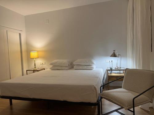 a white bedroom with a bed and a chair at Hotel RL Anibal in Linares