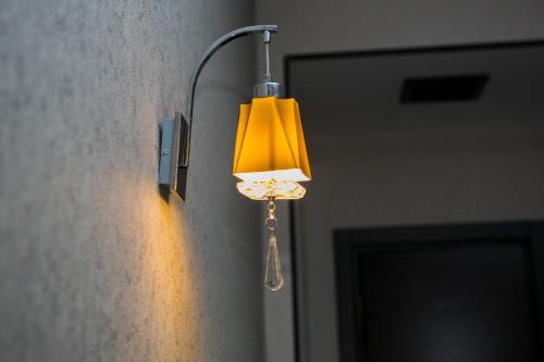 a light on a wall with a yellow lamp on it at Azalea Hotel Baku in Baku