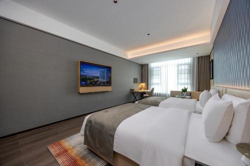 a bedroom with a large bed and a tv on the wall at Lan Ou International Hotel in Ruili