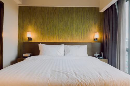 a large bed in a hotel room with two lamps at The Residences at Novotel Tower in Manila