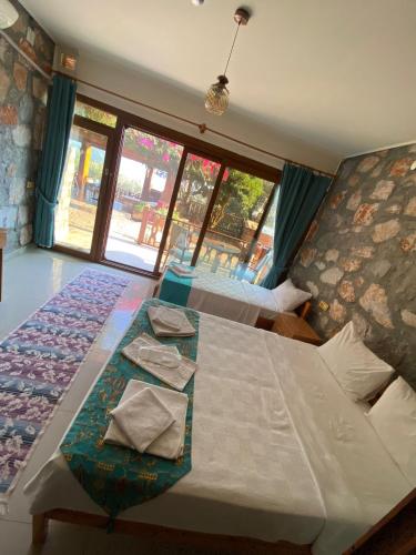 a bedroom with two beds and a large window at Kabak Armes Otel in Fethiye
