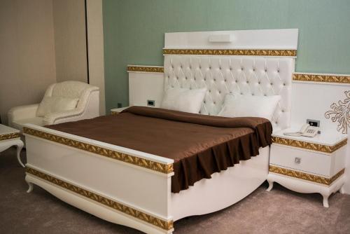 a bedroom with a large white bed and a chair at Azalea Hotel Baku in Baku
