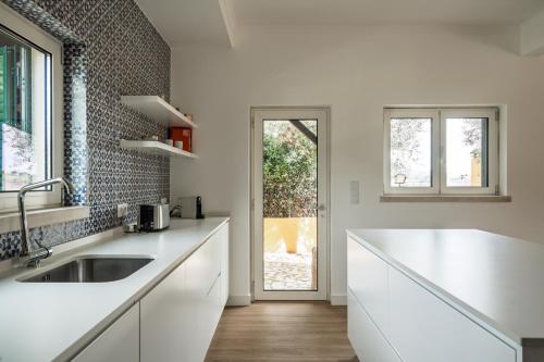a white kitchen with a sink and a window at Bela Vista - Countryside home in Gradil