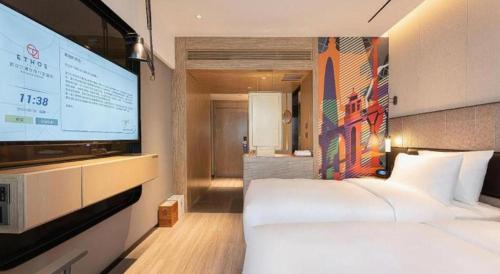 a hotel room with a bed and a large screen at Ethos Hotel Wuhan Riverside in Wuhan