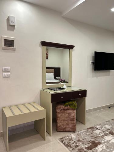 a room with a desk with a mirror and a tv at Jewel Dokki Hotel in Cairo