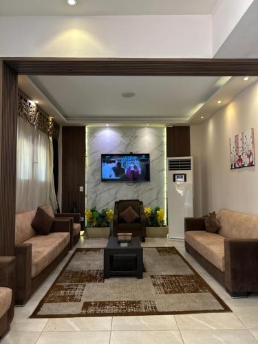 a living room with two couches and a tv on a wall at Jewel Dokki Hotel in Cairo