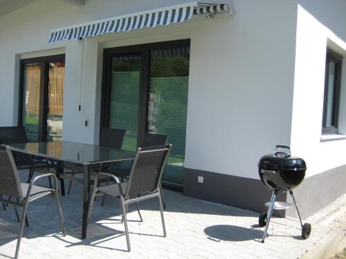 a grill and a table and chairs on a patio at Ferienhaus Silja in Steindorf am Ossiacher See
