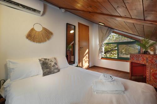 a bedroom with a large white bed with a window at הבית בראש פינה - The House in Rosh Pinna