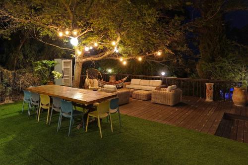 a wooden table and chairs on a deck at night at הבית בראש פינה - The House in Rosh Pinna