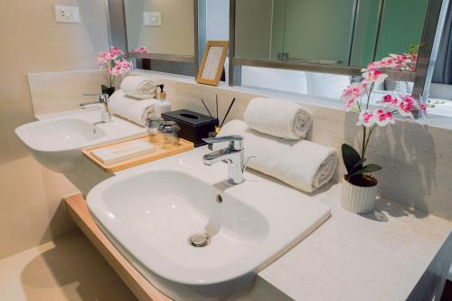 a bathroom with two sinks and a mirror and flowers at The Residences at Novotel Tower in Manila