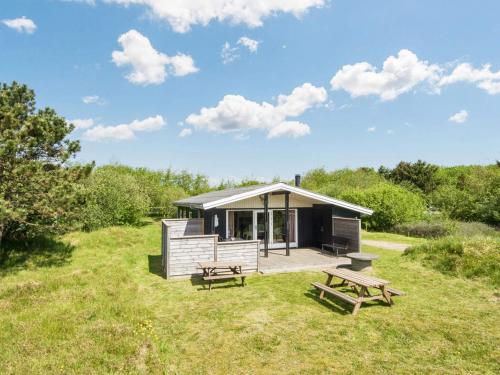 a cabin in a field with two picnic tables at Cozy Sauna House with BBQ - By Traum Ferienwohnungen in Fanø