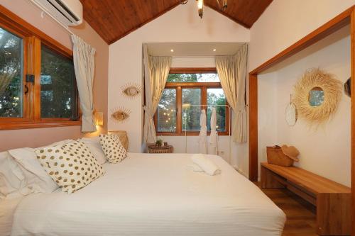 a bedroom with a large bed with white sheets at THE HOUSE ROSH PINA - 3BRM WITH POOl in Rosh Pinna