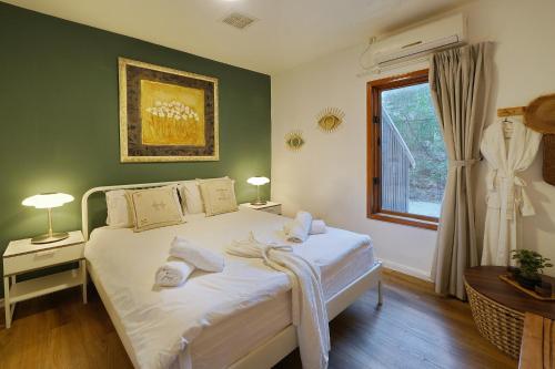 a bedroom with a bed with white sheets and a window at THE HOUSE ROSH PINA - 3BRM WITH POOl in Rosh Pinna
