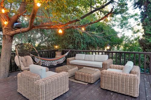 a patio with wicker chairs and a hammock on a deck at THE HOUSE ROSH PINA - 3BRM WITH POOl in Rosh Pinna