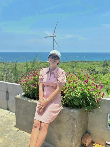a woman standing next to a wall with a wind turbine at Homestay Hoàng Phúc in Cu Lao Thu