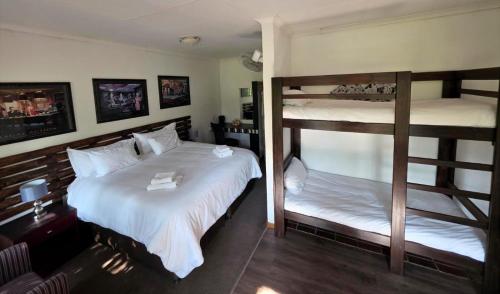 a bedroom with two bunk beds with white sheets at Wayside Lodge in Waterval Boven