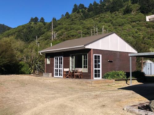 eine kleine Hütte mit einem Tisch und Stühlen vor einem Berg in der Unterkunft The Cottage in Waikawa in Waikawa