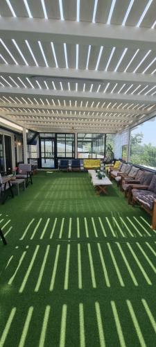 a large room with a green floor with chairs and tables at Moon View Resort in Ein Kinya