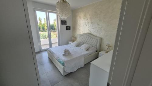 a white bedroom with a bed and a window at La dimora di Matteo in Marina di Montenero