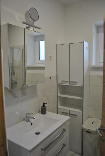 a white bathroom with a sink and a mirror at Prenočišča Dany APARTMA 1 in Dravograd