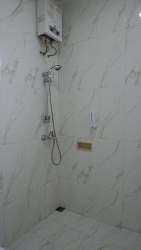 a shower in a bathroom with white marble walls at Villa Dalia Puncak P2-12 in Cianjur