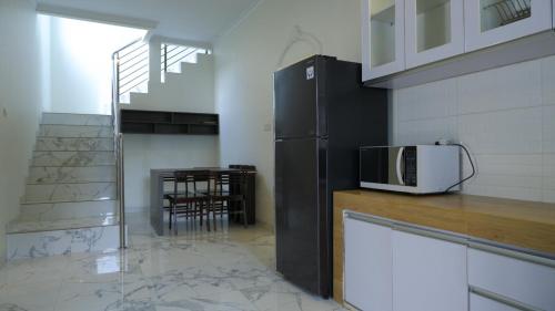 a kitchen with a black refrigerator and a microwave at Villa Dalia Puncak P2-12 in Tjiandjur