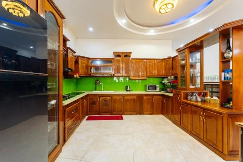 a kitchen with wooden cabinets and green walls at Hoi An Legend Connect Villa in Hoi An