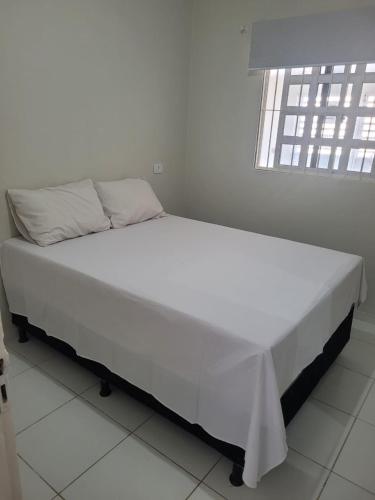 un letto bianco in una stanza con una finestra di Casa São José da Coroa Grande a São José da Coroa Grande