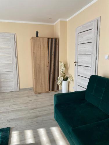 a living room with a green couch and a cabinet at Apartament Koszarawa in Koszarawa