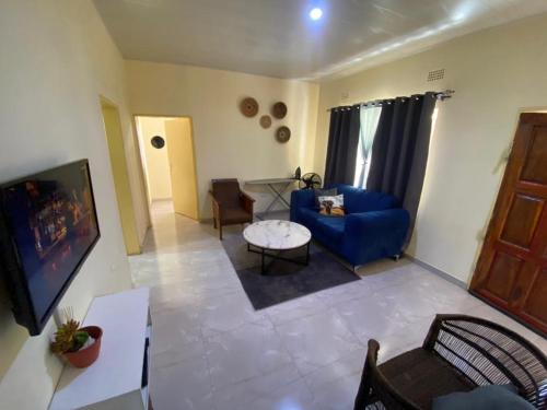 a living room with a blue couch and a tv at Natulu Apartment Livingstone in Livingstone