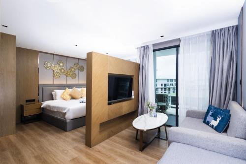 a hotel room with a bed and a couch at Suite Aura 1BR PoolsGyms Shuttle to Nai Harn in Rawai Beach