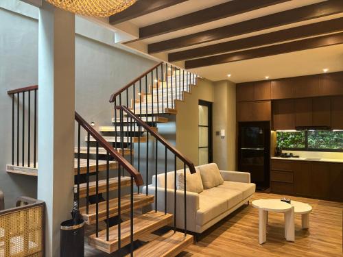 a living room with a staircase with a couch and a table at Hygge Hotel and Villas Seminyak in Seminyak
