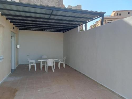 a patio with a table and chairs in a white wall at Appartement familial et calme proche des plages & Alger in Mahelma